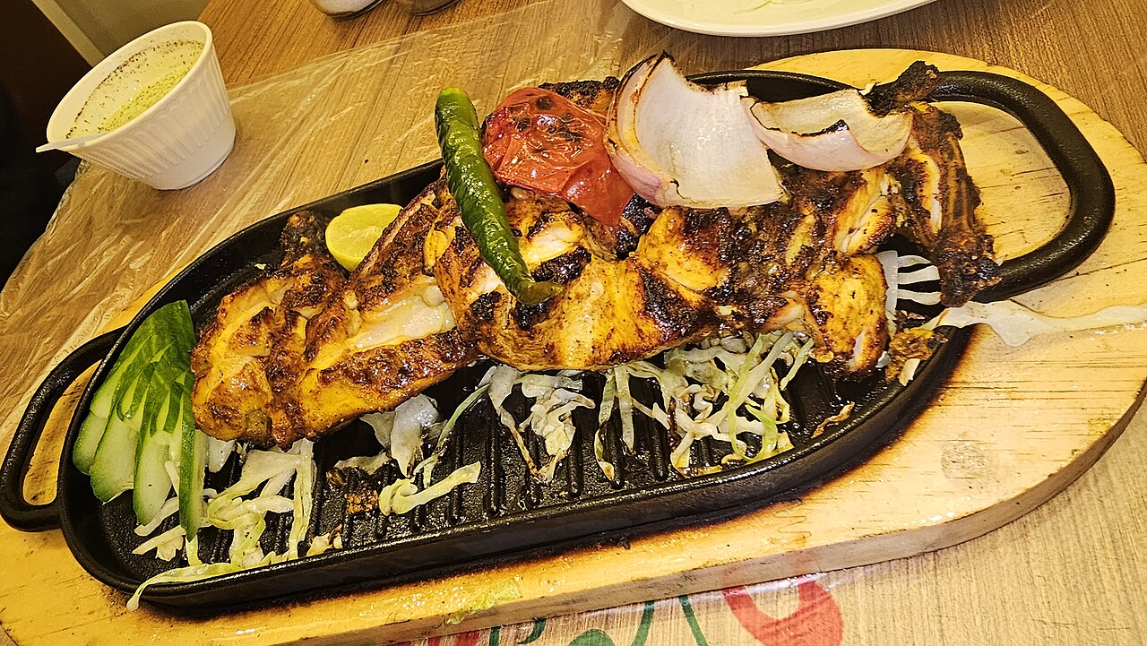 Chicken tikka pieces with charred edges on a plate