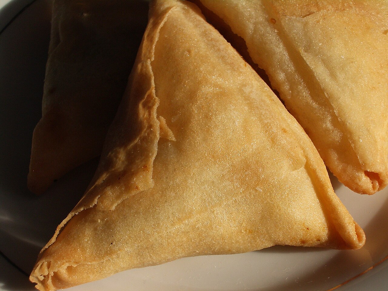 Fried samosas stacked on a plate