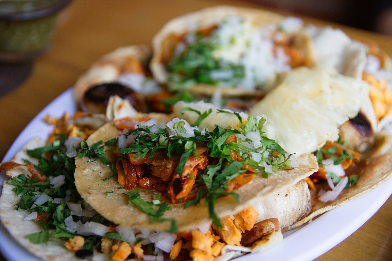 Tacos filled with meat, onion and salsa on a plate